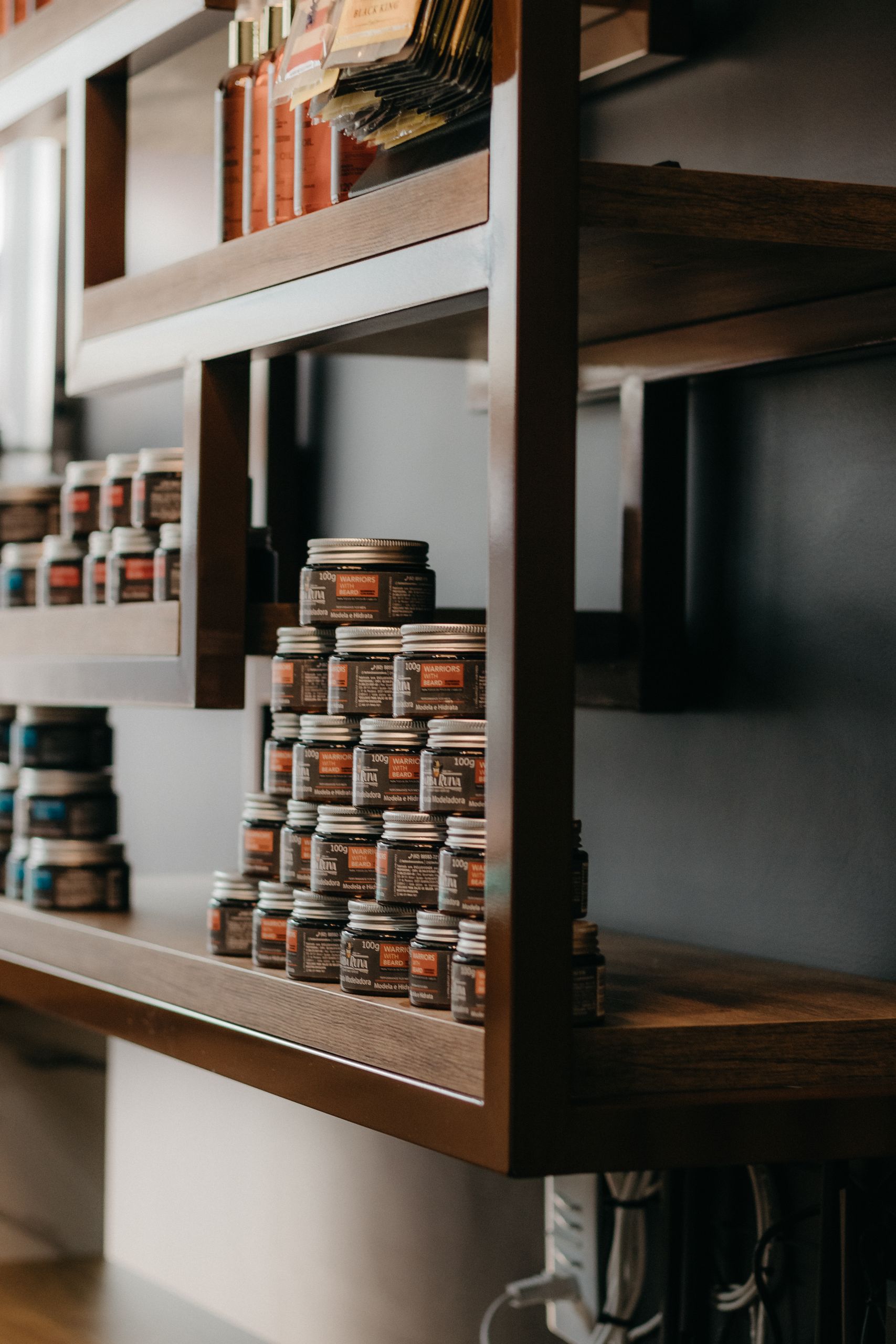 A neat display of haircare products in glass jars on wooden shelves at a modern hair salon.