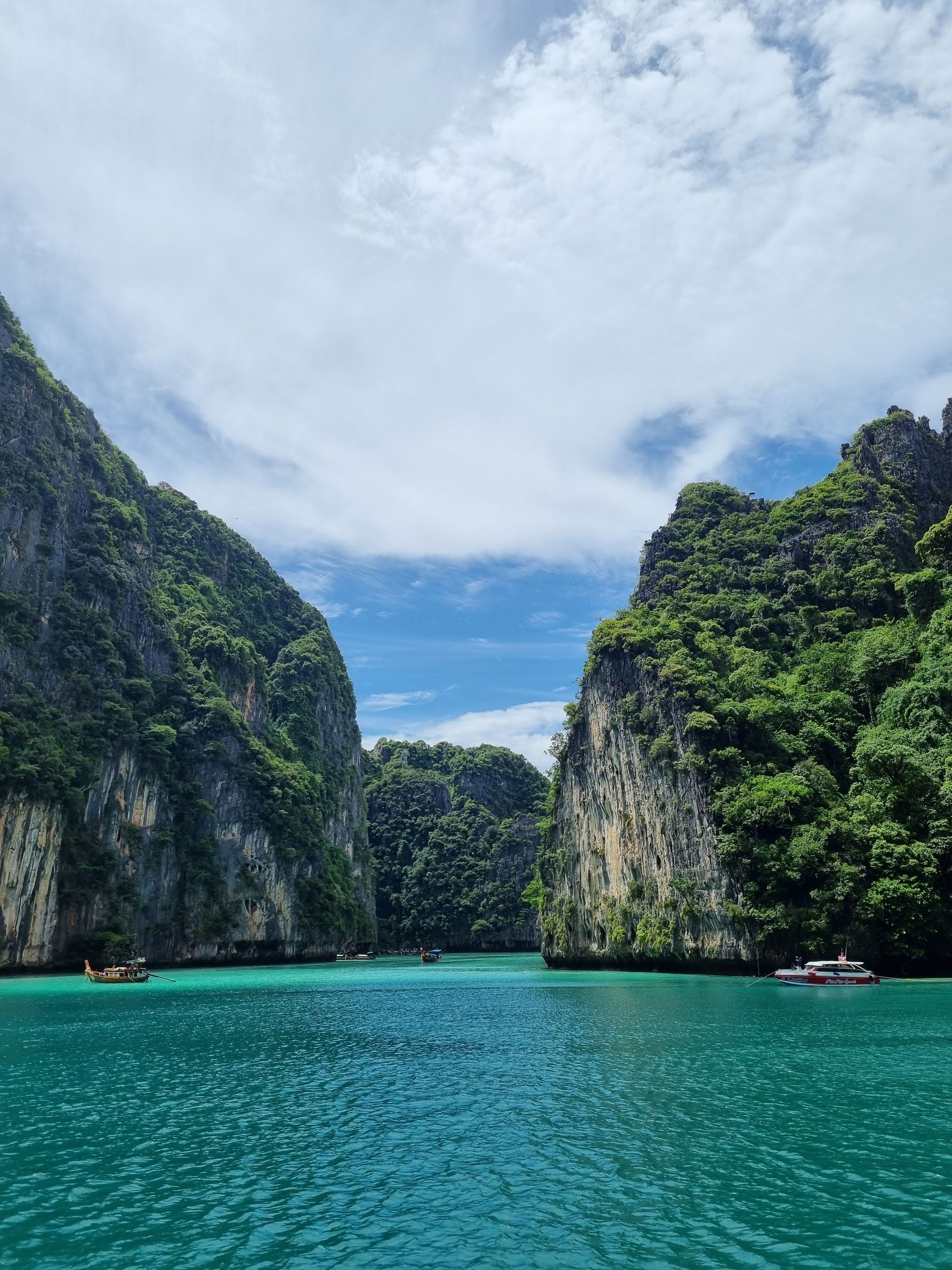Pristine turquoise waters surrounded by lush limestone cliffs under a bright sky.
