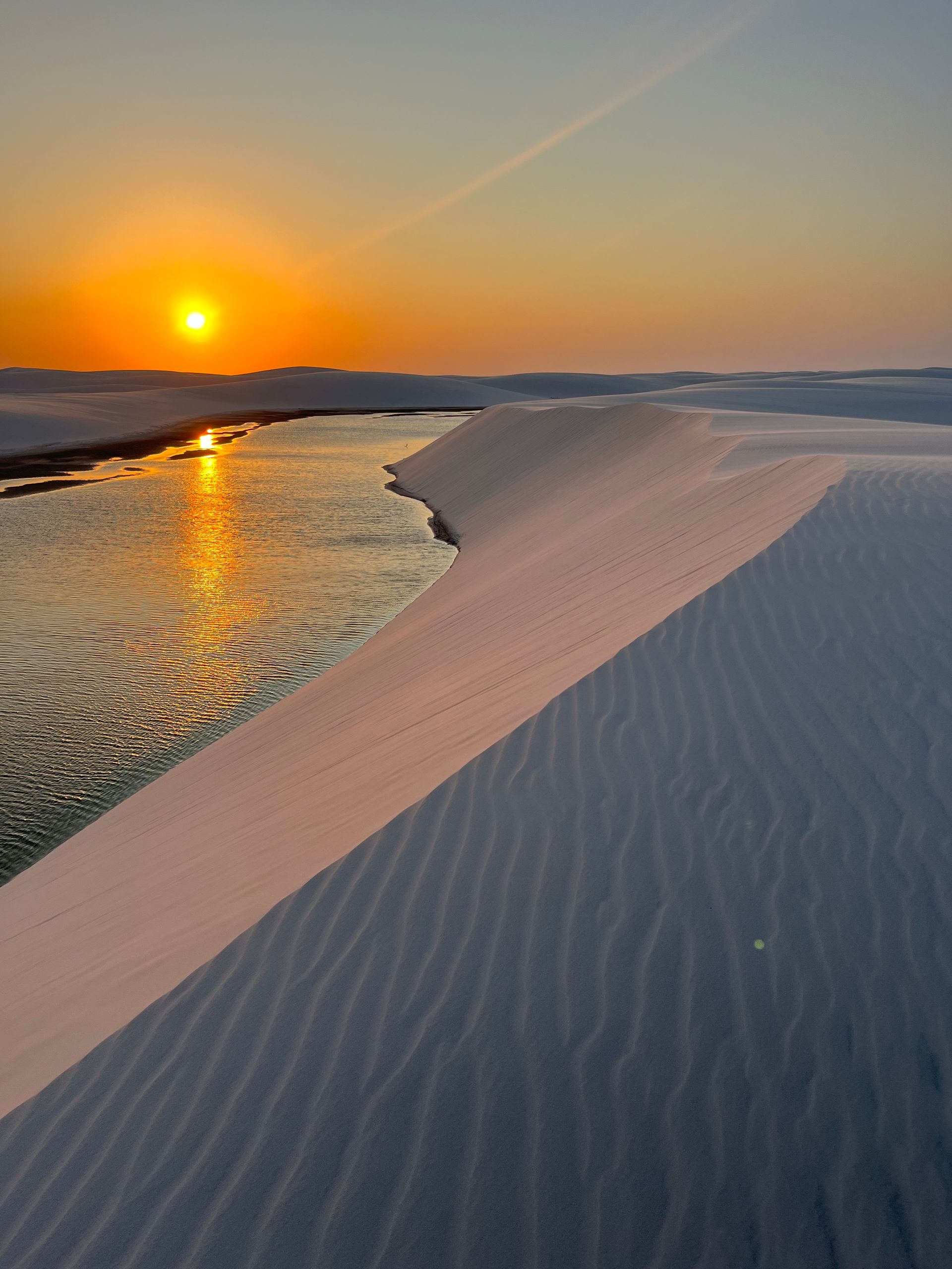 Stunning sunset over sand dunes and lagoon at Lençóis Maranhenses, Brazil.