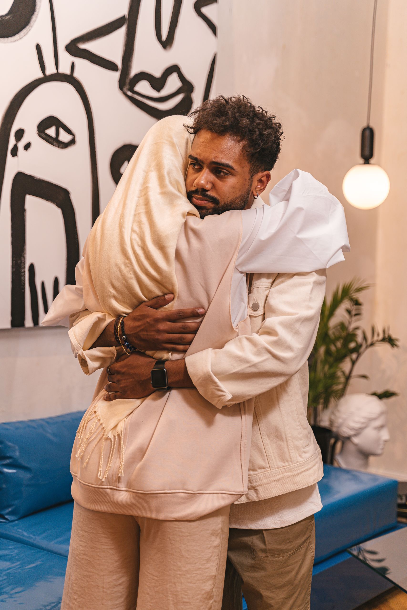A couple shares a heartfelt embrace in a stylish living room with modern art.