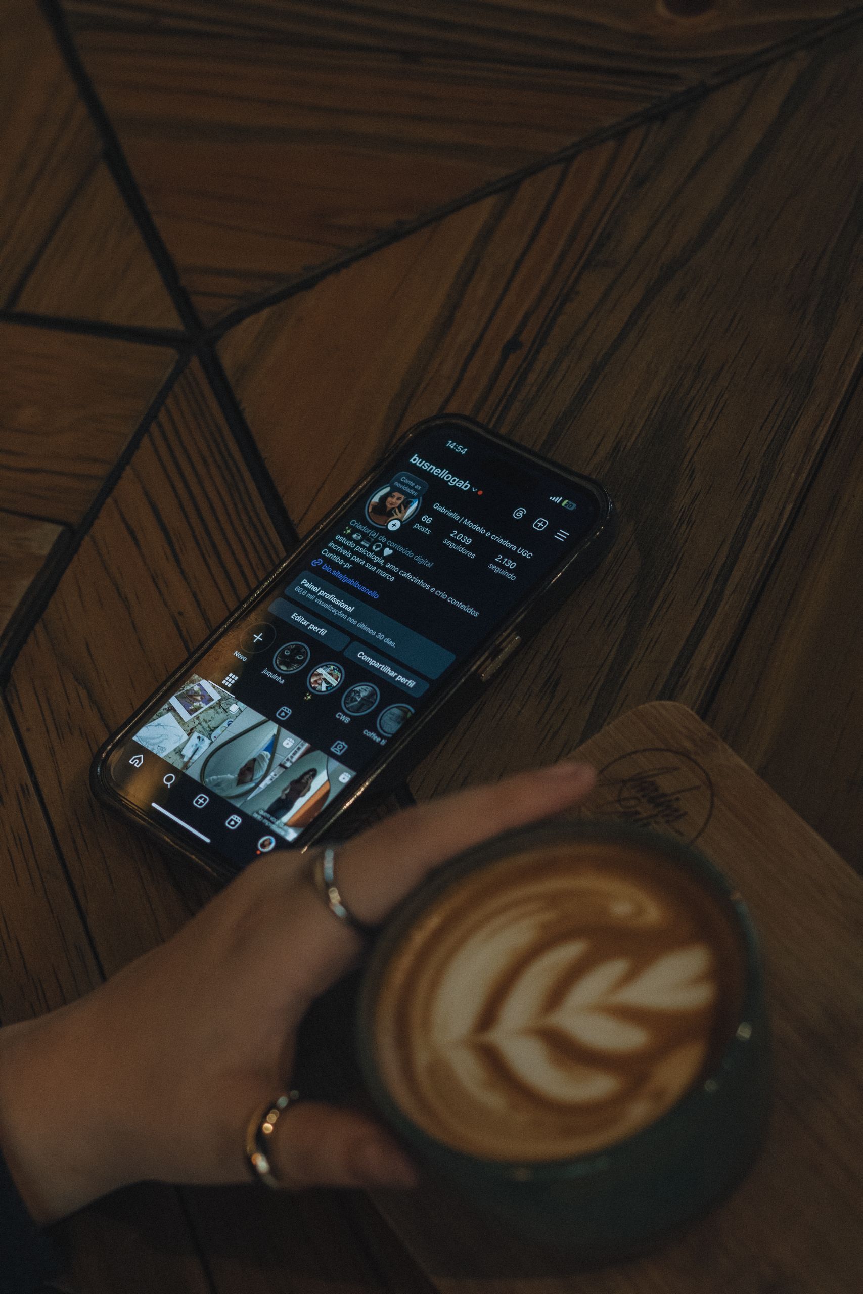 A cozy cafe scene featuring a latte art coffee and a stylish smartphone showing a social media profile.