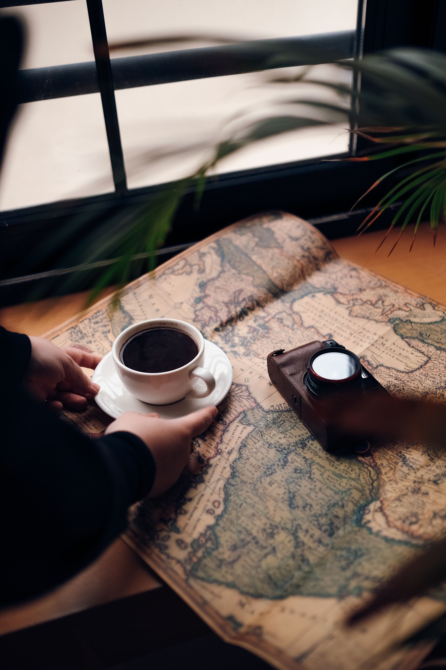 A cozy scene featuring a cup of coffee on a vintage map with a retro camera, evoking a sense of exploration.
