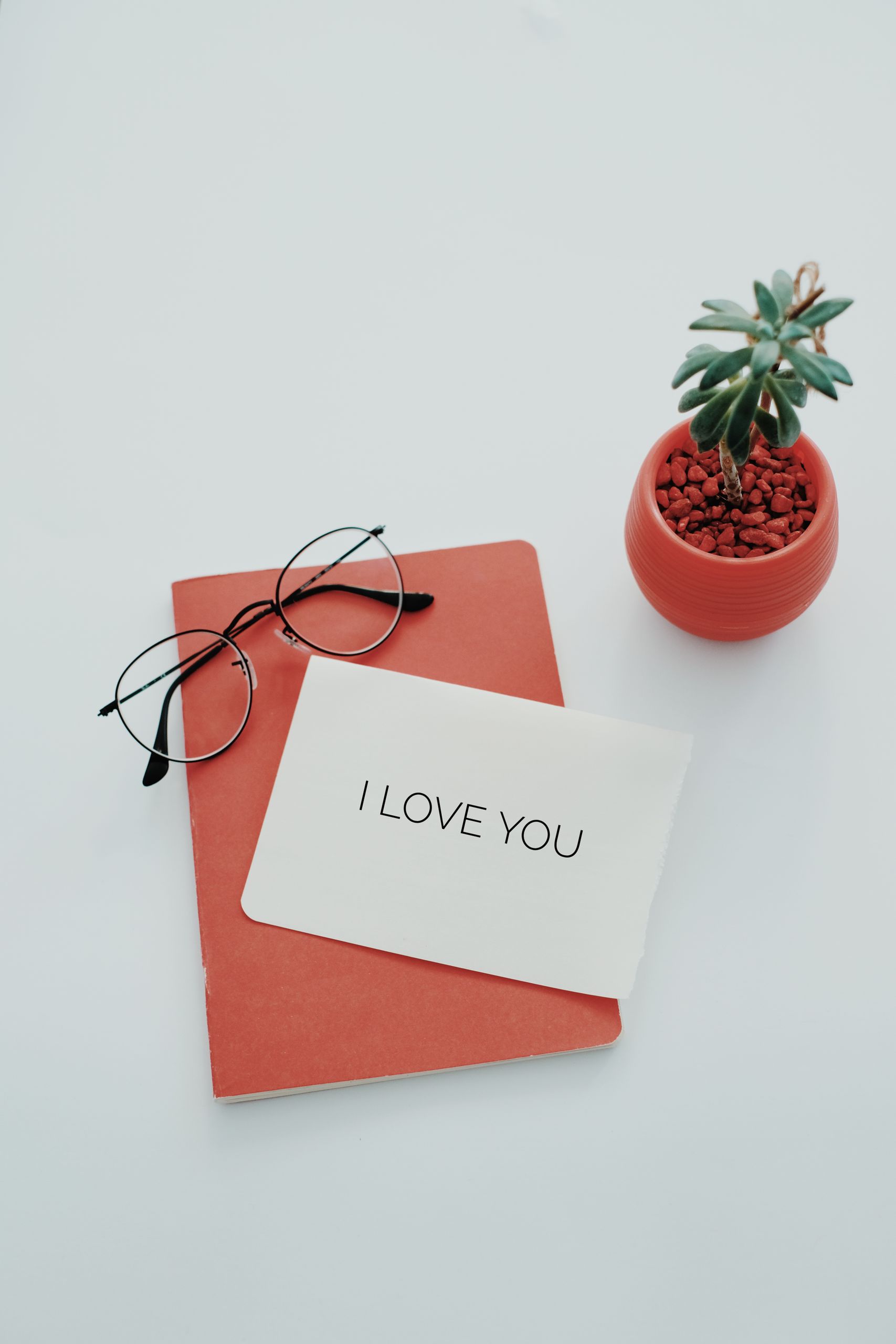 A romantic note saying 'I love you' with eyeglasses and a succulent plant on a notebook.
