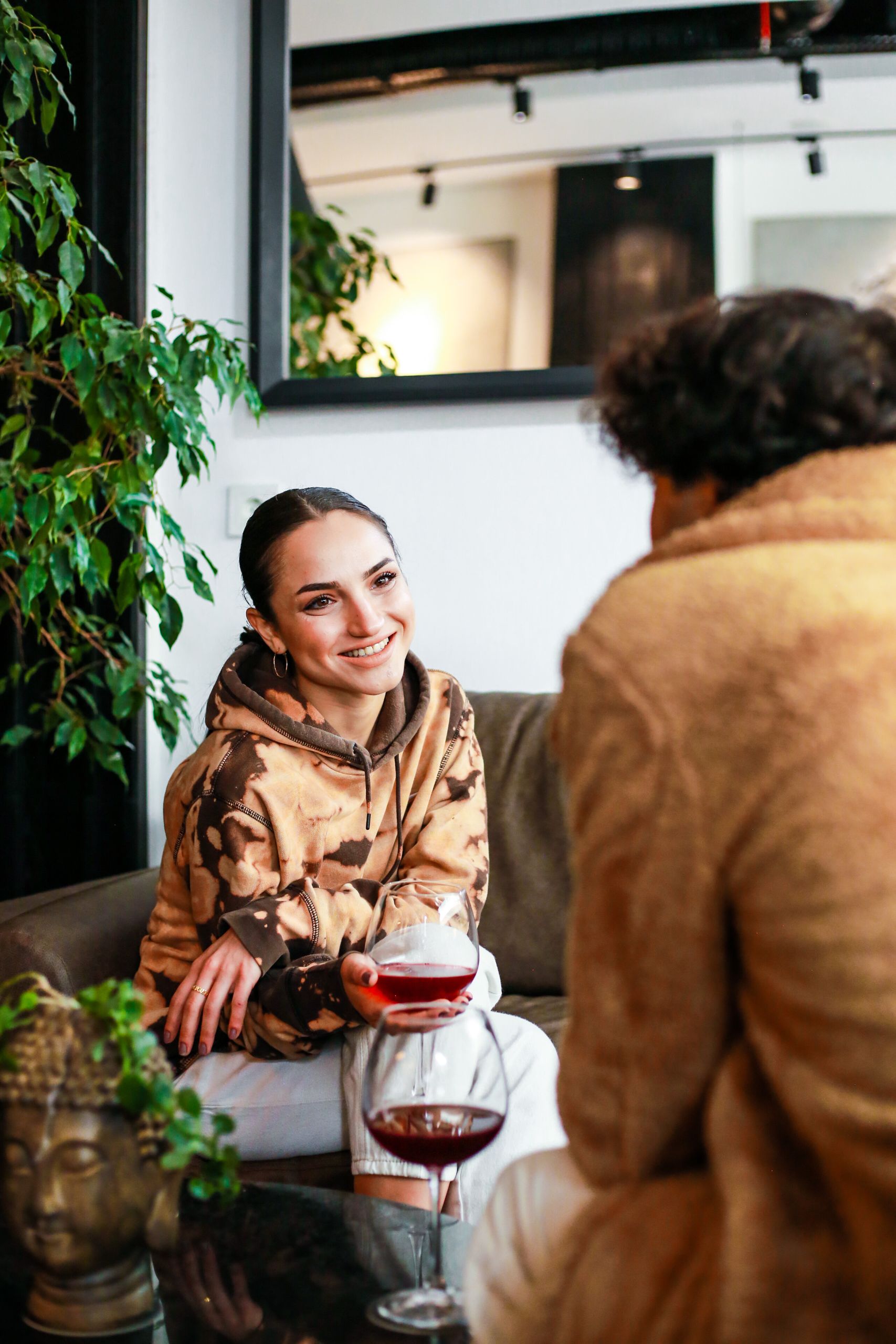A woman and a man enjoying a relaxed conversation over a glass of red wine indoors.