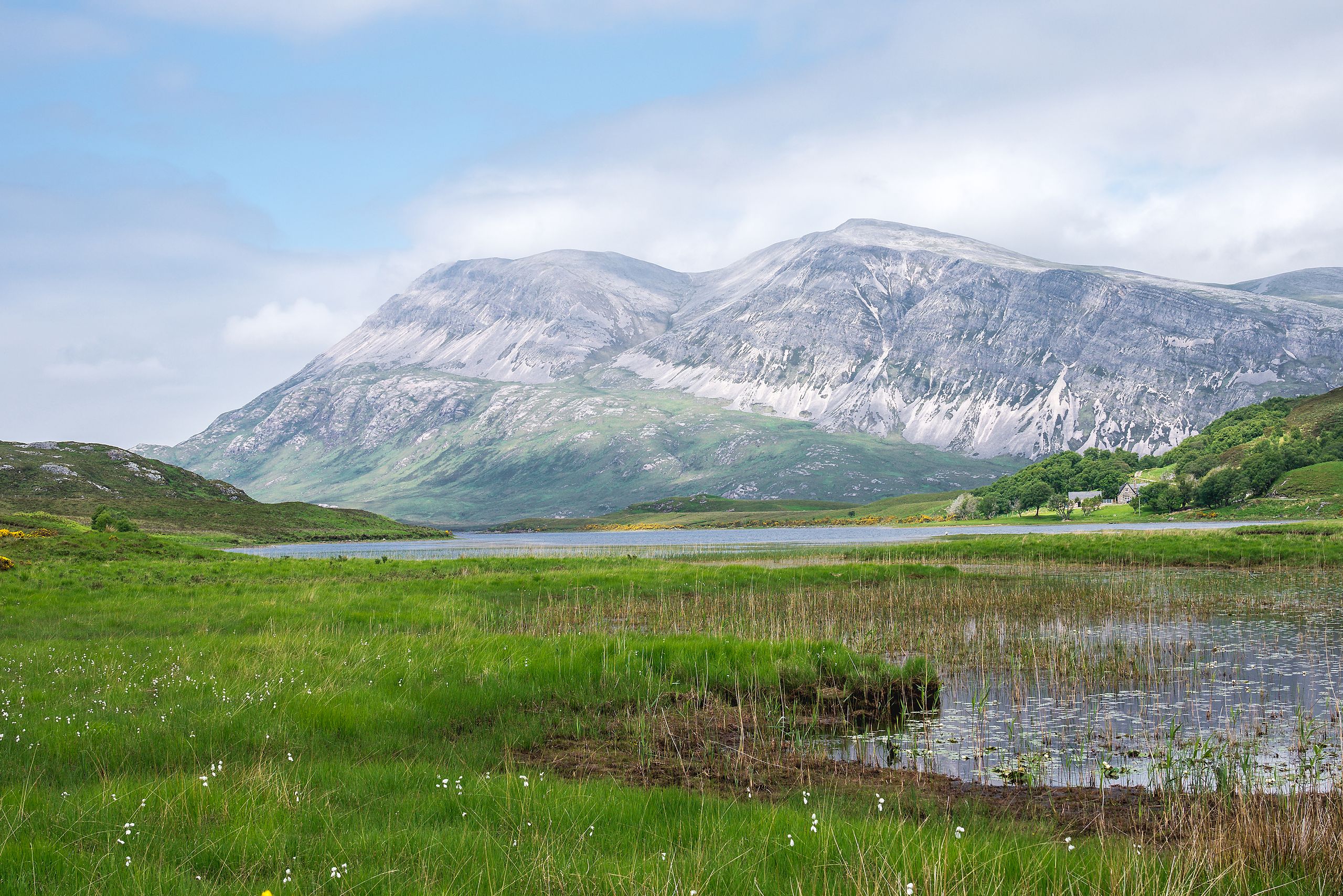 Beautiful landscape of Arkle Mountain with green meadows and a lake in Sutherland, Scotland.