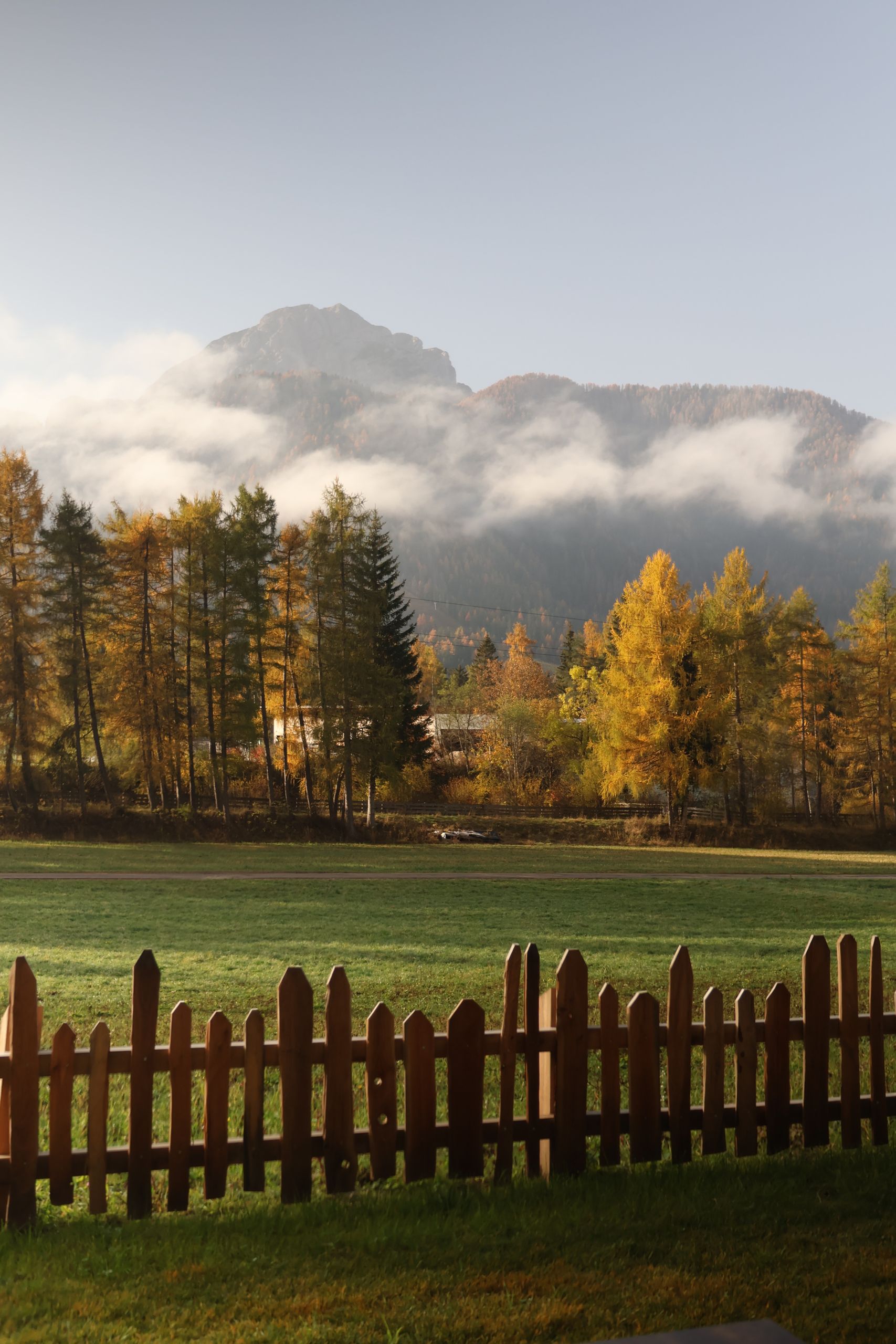 Captivating autumn landscape of Dolomites, Italy with misty mountains and vibrant foliage.