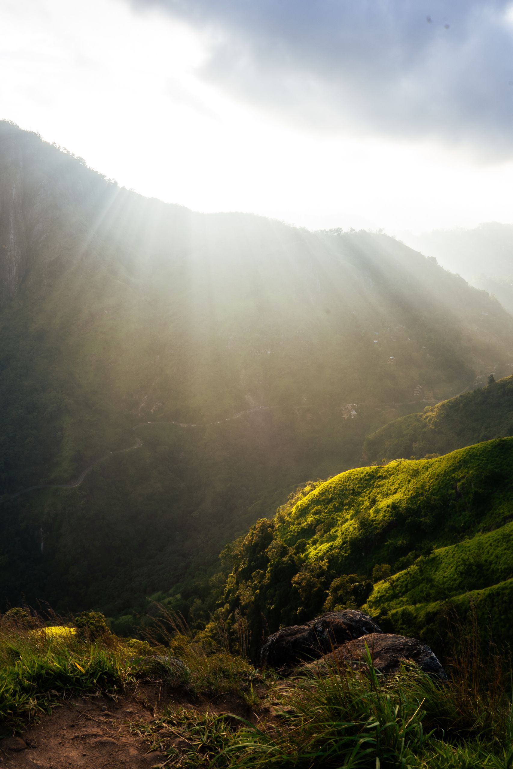 Dramatic sunrays illuminate a verdant mountain valley, creating a captivating natural scene.