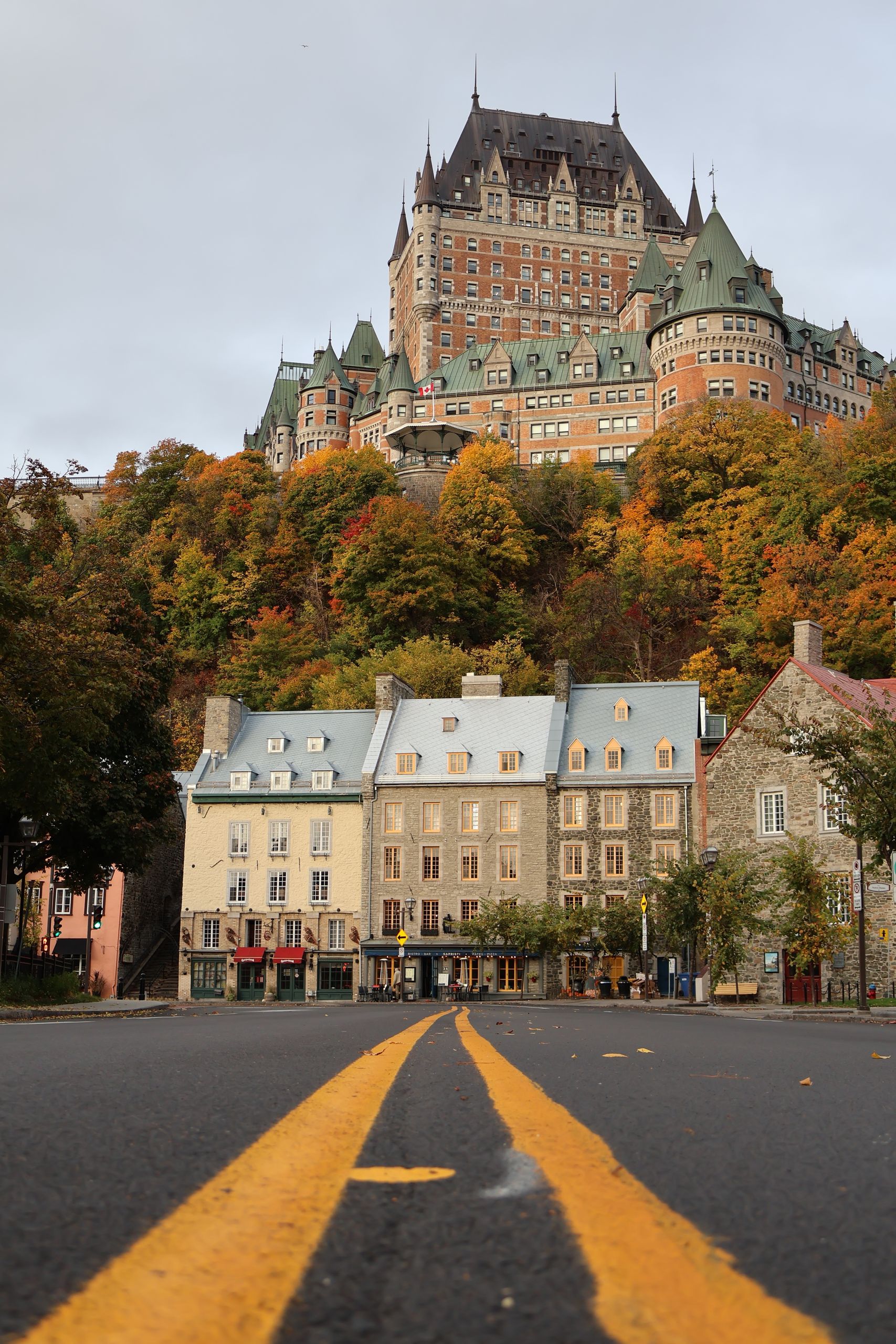 Enchanting autumn view of Château Frontenac rising above historic buildings and colorful foliage in Québec City.
