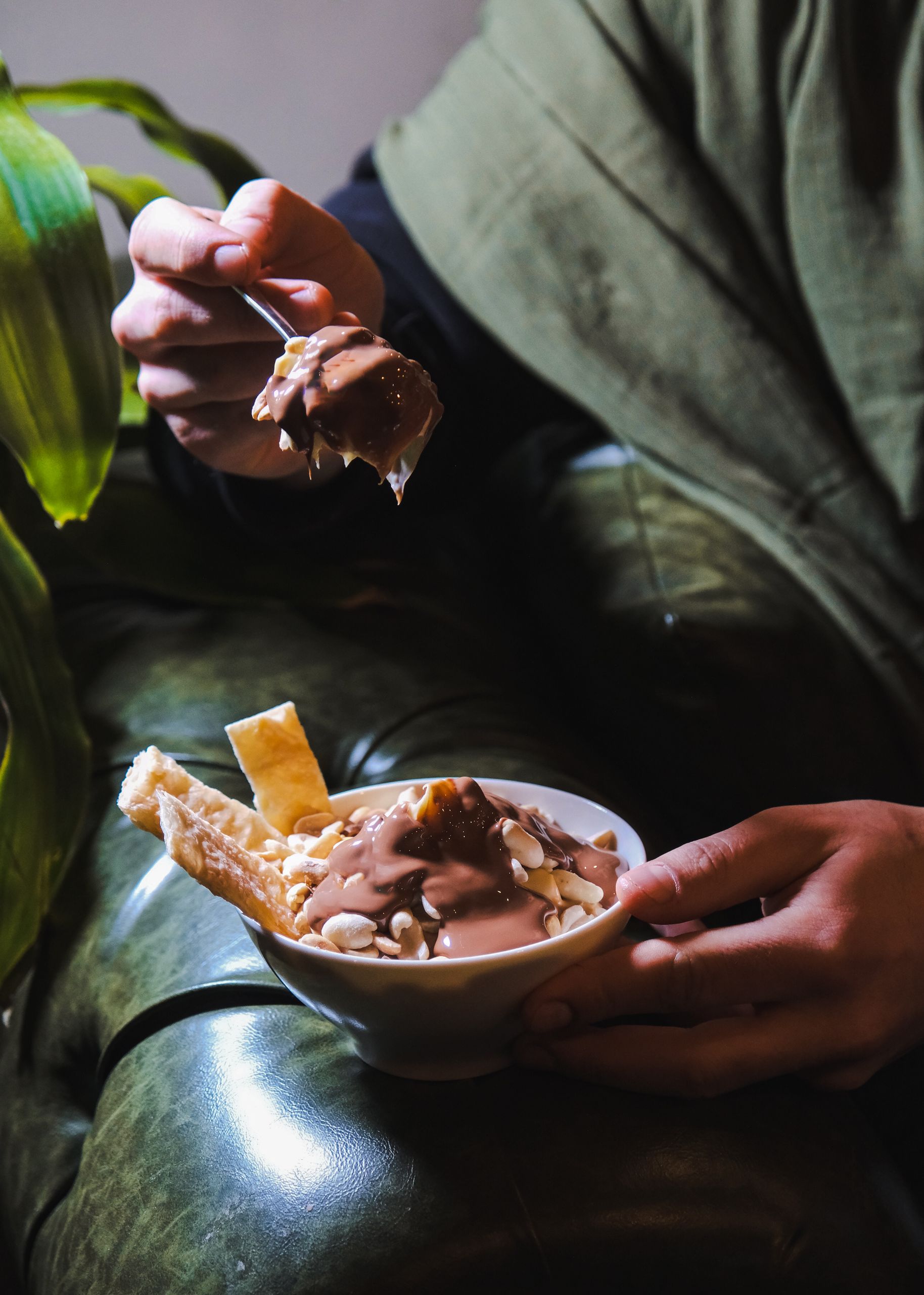 Indulge in a rich chocolate dessert garnished with nuts and crispy wafers in a cozy indoor setting.
