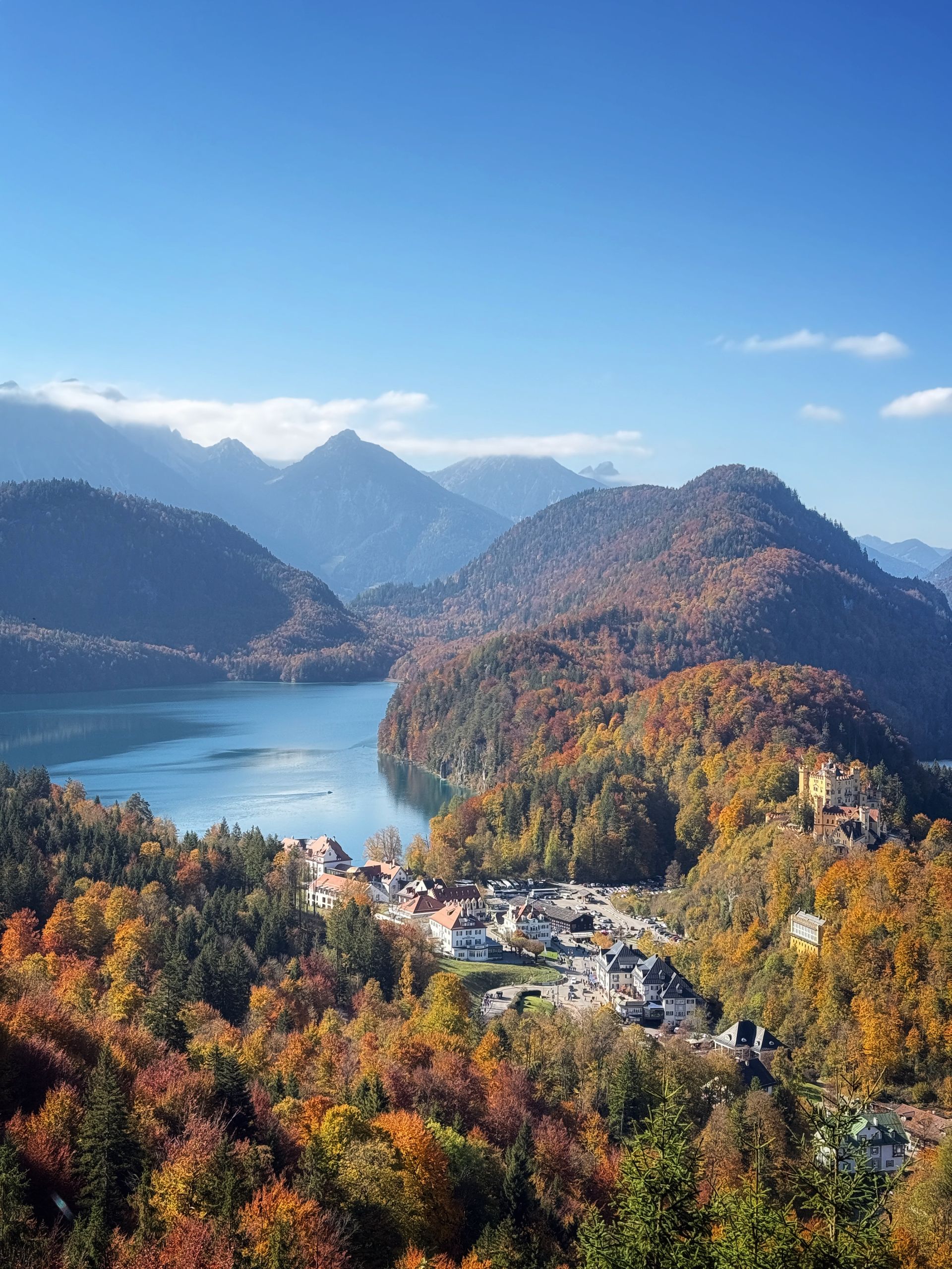 Majestic view of Neuschwanstein Castle surrounded by autumn foliage and mountains in Bavaria, Germany.