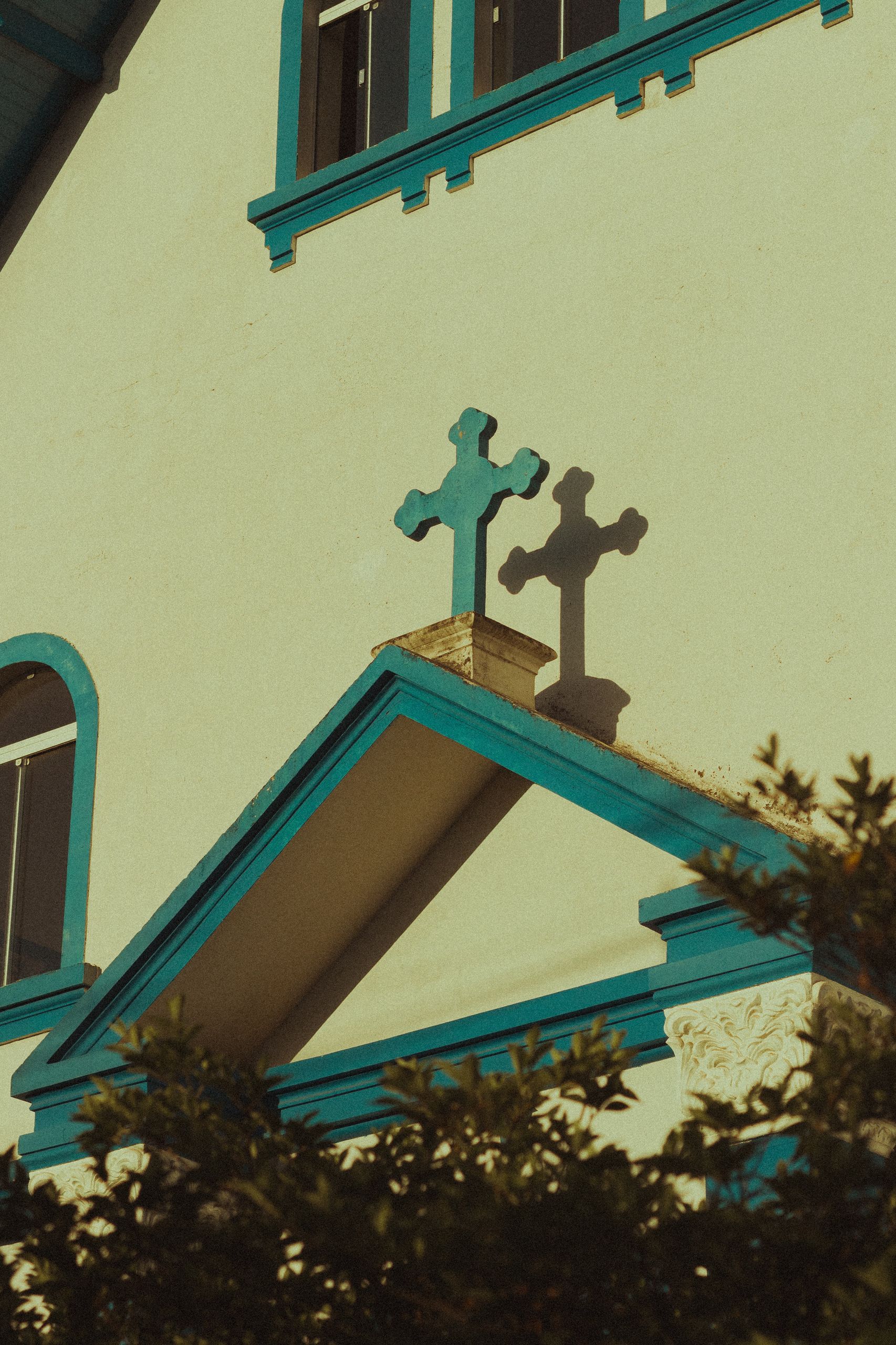 Vertical shot of a church facade featuring wooden crosses and intricate blue trim, symbolizing Christianity.
