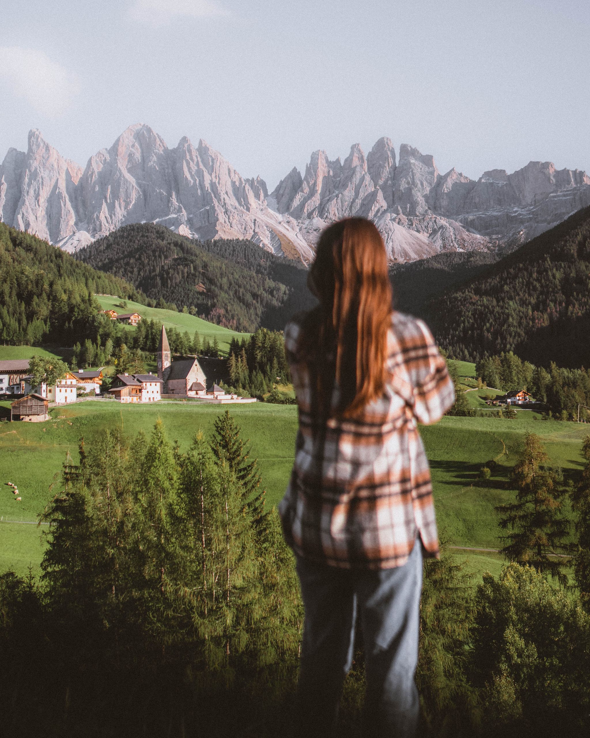Woman stands in awe at the picturesque St. Magdalena village in the Dolomites.