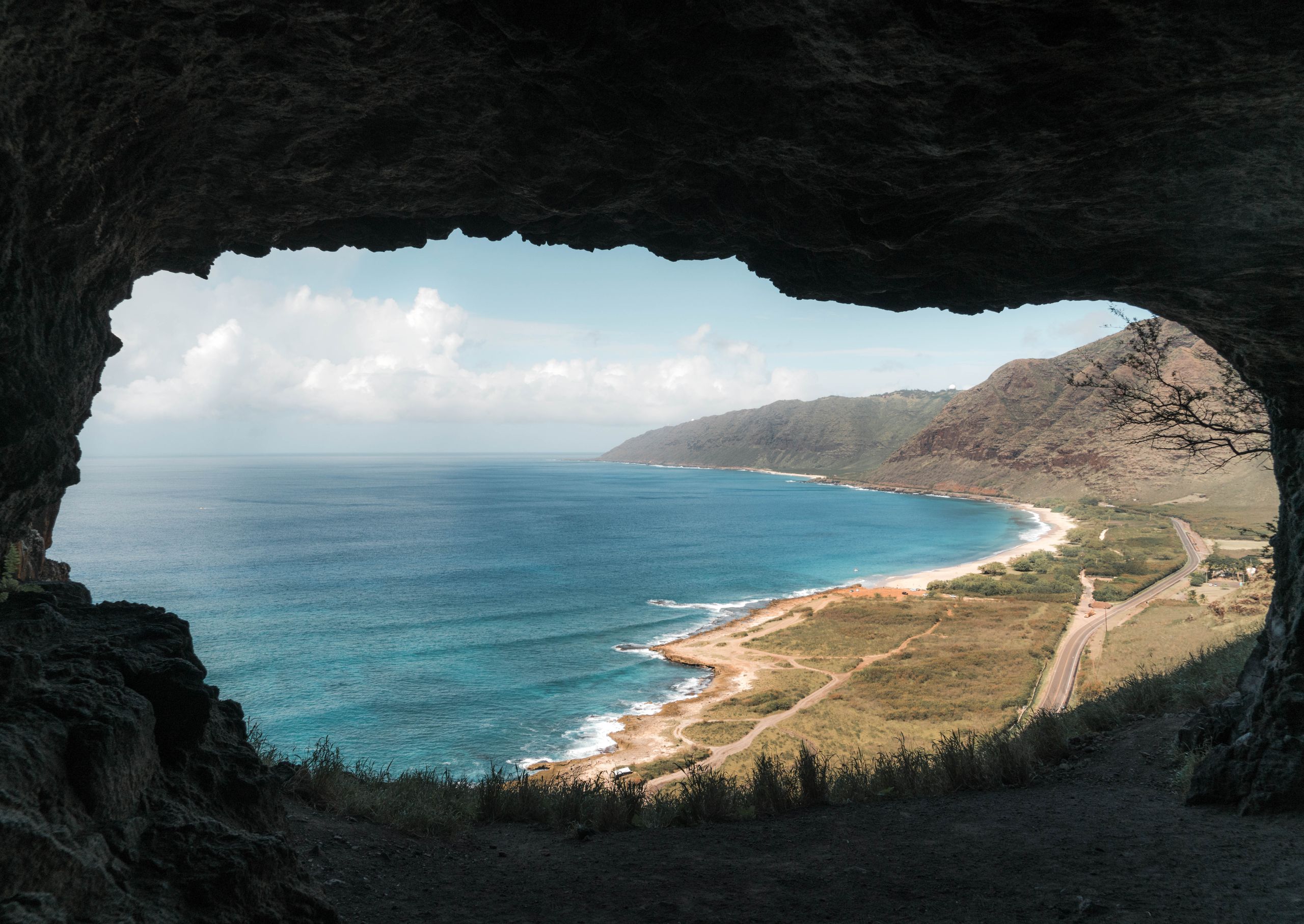 Stunning coastal landscape viewed from a cave, with ocean waves and scenic horizon.